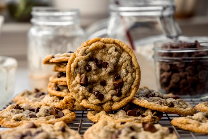 Sourdough discard chocolate chip cookies on a cooling rack with jars behind it.