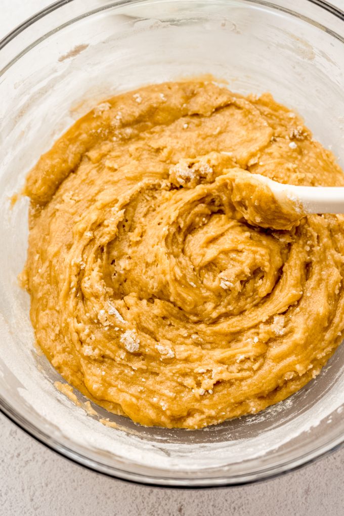 Sourdough discard chocolate chip cookie dough in a bowl being stirred with a spatula.