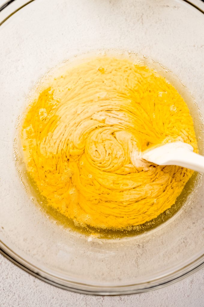 Browned butter and sourdough discard being stirred together in a bowl with a spatula.