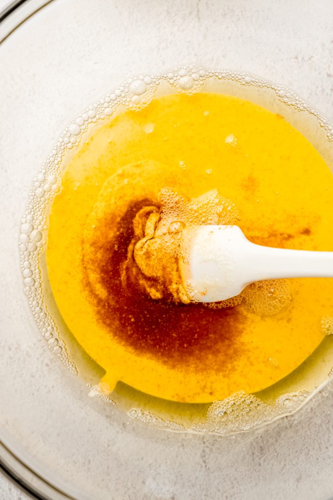 Browned butter and sourdough discard being stirred together in a bowl with a spatula.