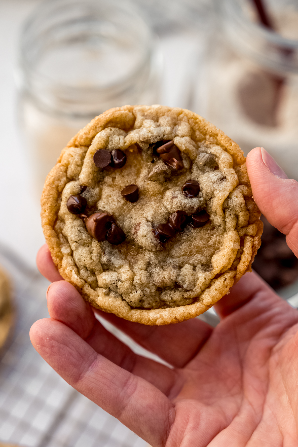 Someone's hand holding a sourdough chocolate chip cookie in it.