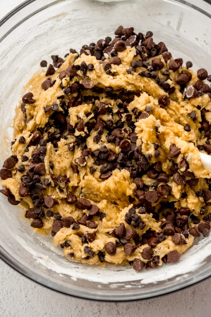 Sourdough discard chocolate chip cookie dough in a bowl being stirred with a spatula.