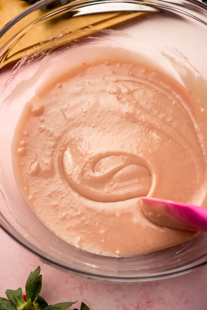 Someone is stirring a bowl of strawberry truffle filling.