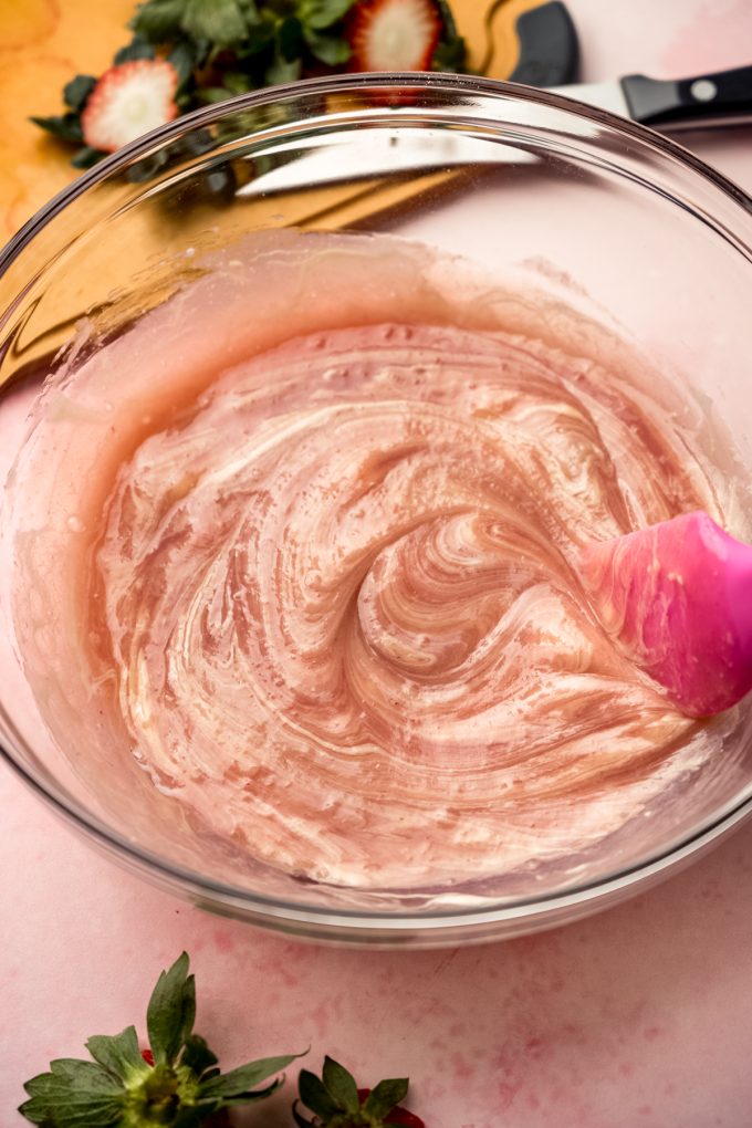 Someone is stirring a bowl of strawberry truffle filling.