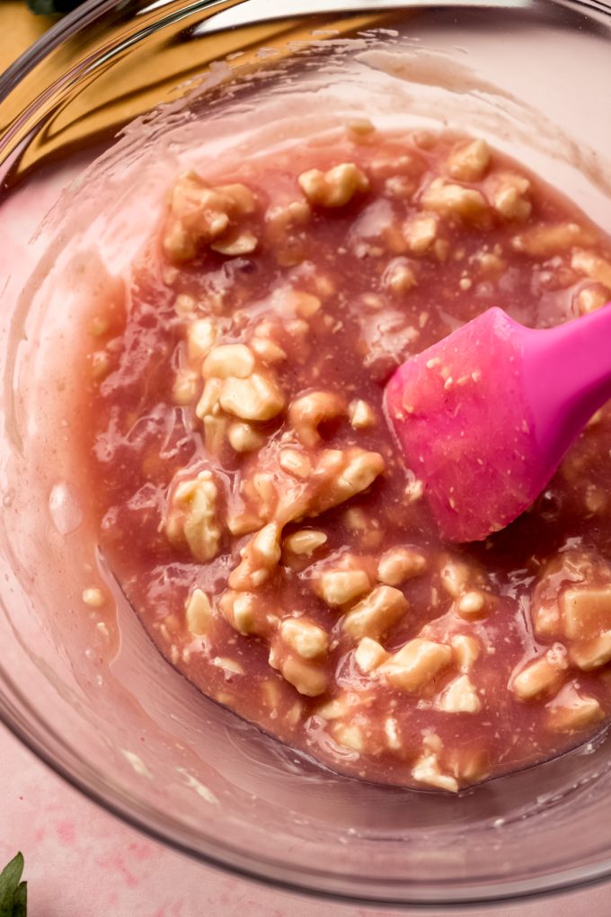 Someone is stirring a bowl of strawberry truffle filling.