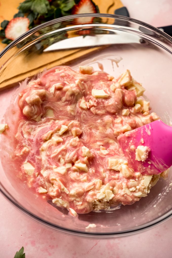 Someone is stirring a bowl of strawberry truffle filling.