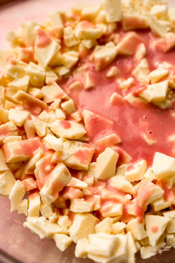 White chocolate chunks and strawberry puree in a bowl to make strawberry truffles.