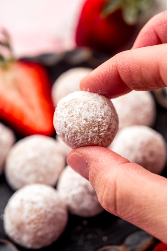 Someone's hand holding a strawberry truffle.