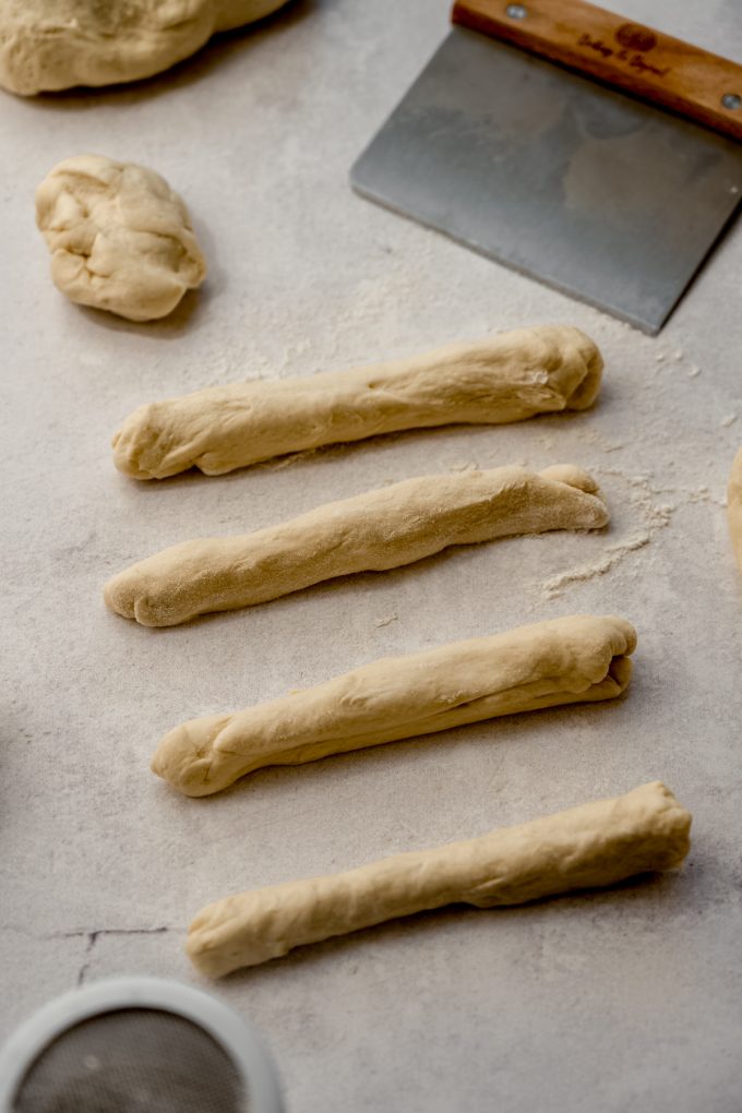 Homemade breadsticks dough on a surface.