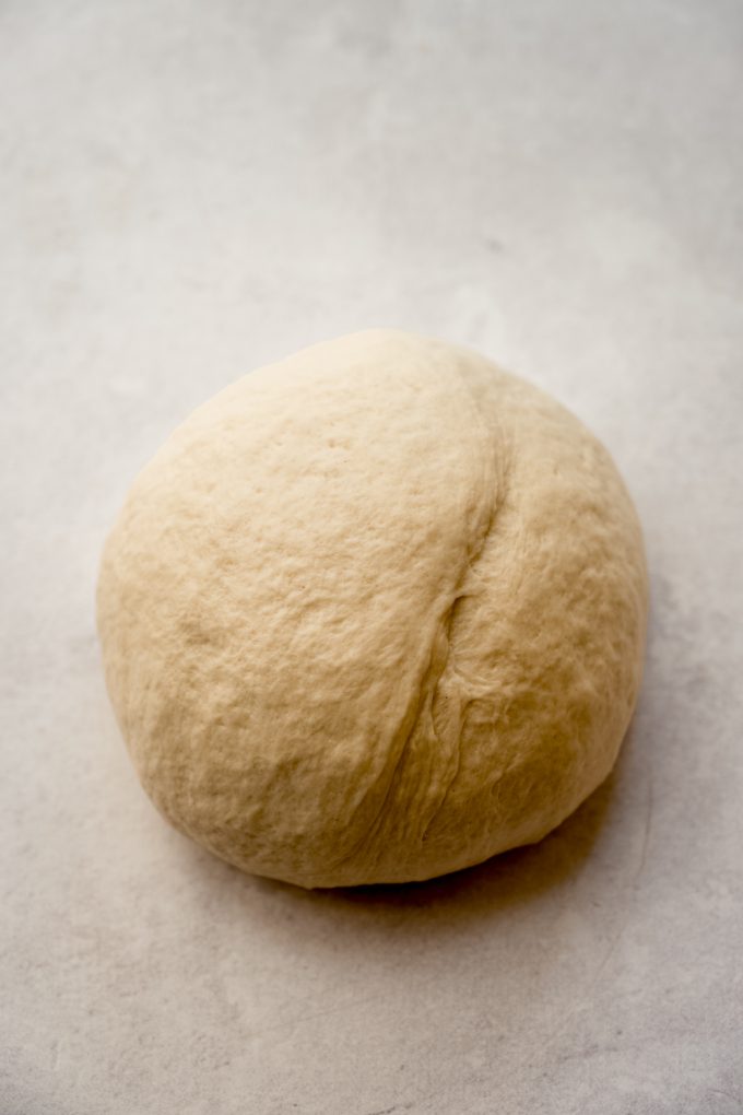 A ball of yeasted bread dough on a surface.