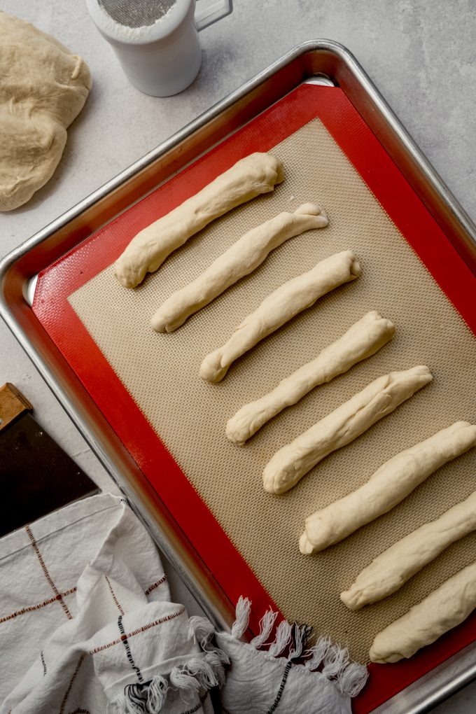 Aerial photo of homemade breadsticks on a baking sheet before baking.