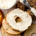 Aerial photo of homemade bagels and one has been split and spread with cream cheese.