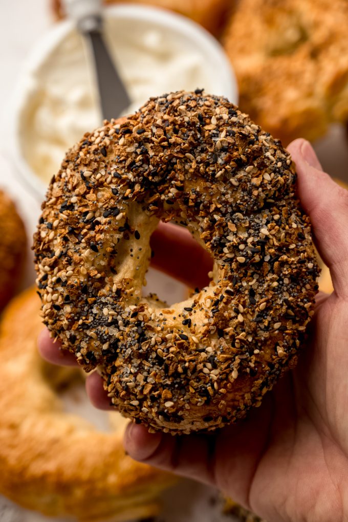 Someone is holding a homemade everything bagel in their hand.