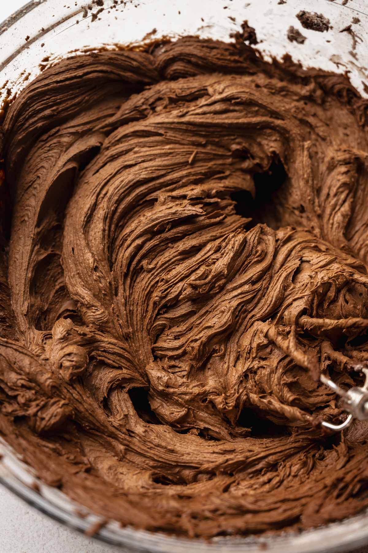 A bowl of malted milk chocolate buttercream with electric beaters in it.