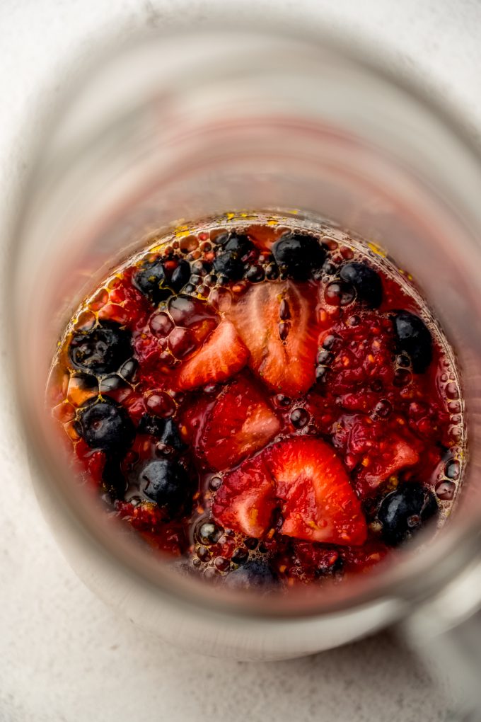 Aerial photo of the fruit mixture for berry sangria in a glass pitcher.