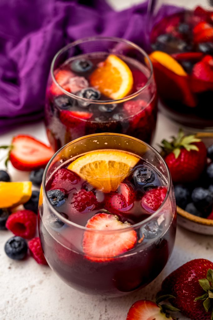Two glasses of berry sangria on a surface.