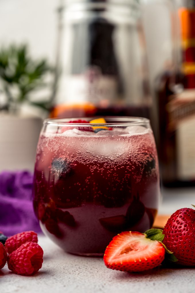 A glass of berry sangria on a surface.