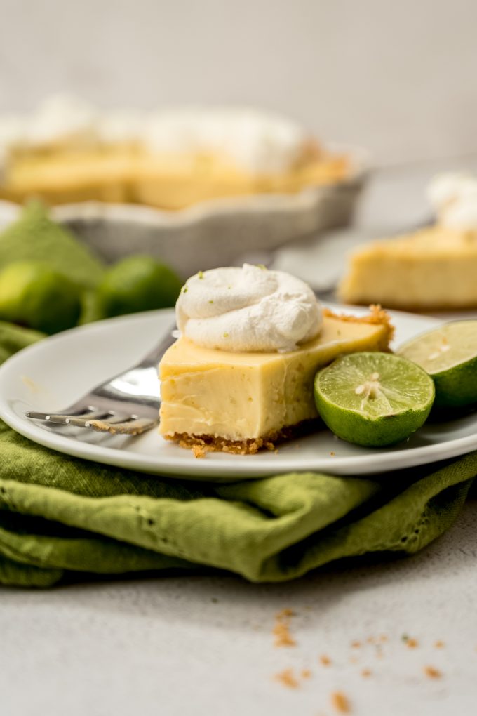 A photo of a slice of Key lime pie on a plate with a fork and a bite taken out of the slice.