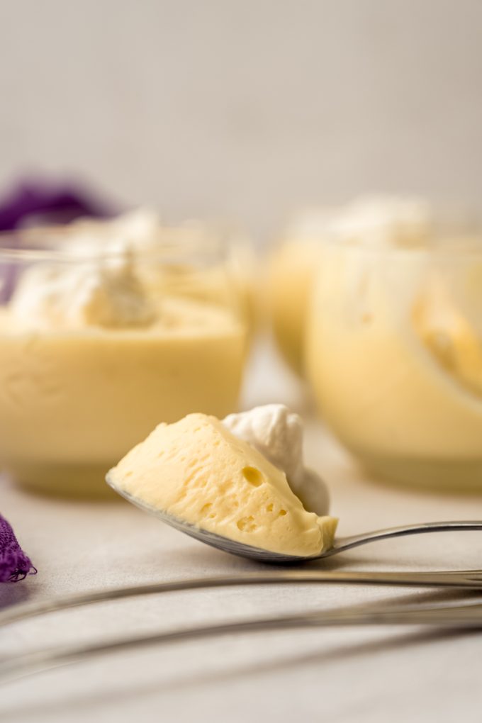 A spoon with a bite of passion fruit mousse on it.