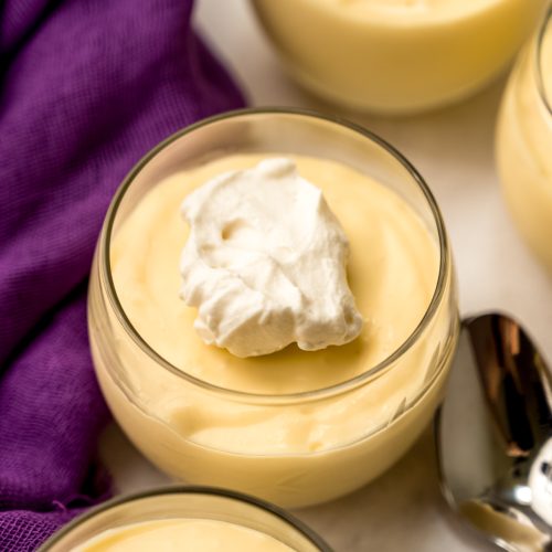 A dessert cup with passion fruit mousse in it and the mousse has a dollop of whipped cream on top.