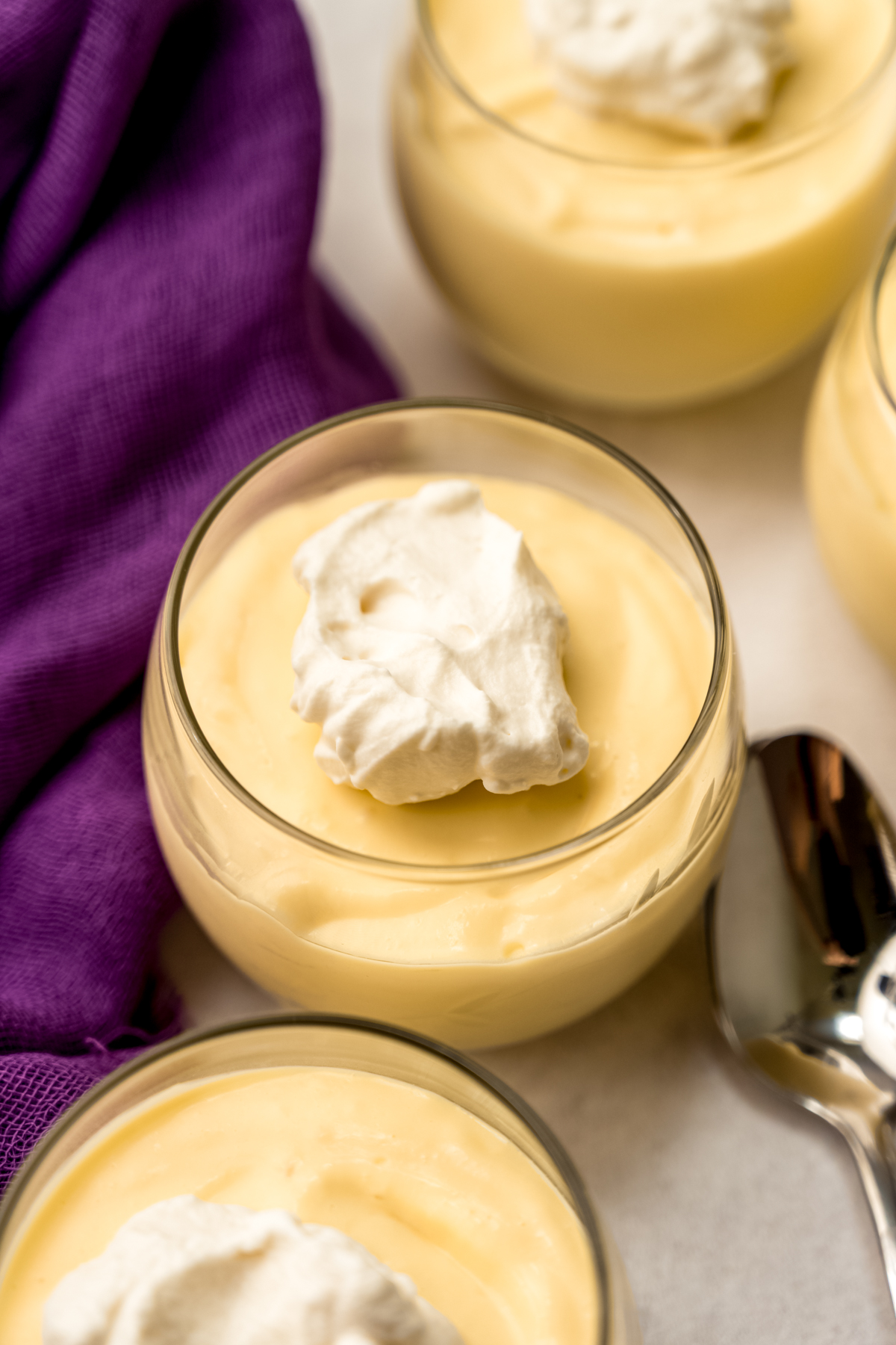 A dessert cup with passion fruit mousse in it and the mousse has a dollop of whipped cream on top.