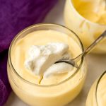 A photo of someone putting a spoon into a cup of passion fruit mousse.