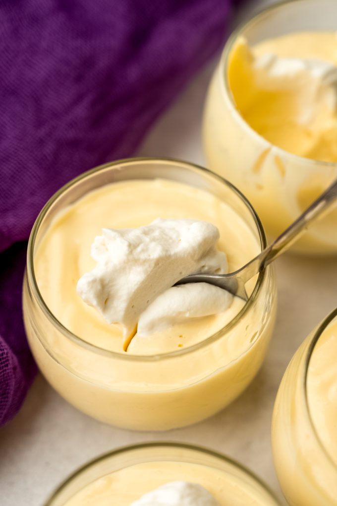 A photo of someone putting a spoon into a cup of passion fruit mousse.