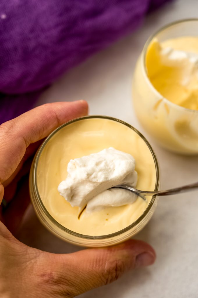 A photo of someone putting a spoon into a cup of passion fruit mousse.