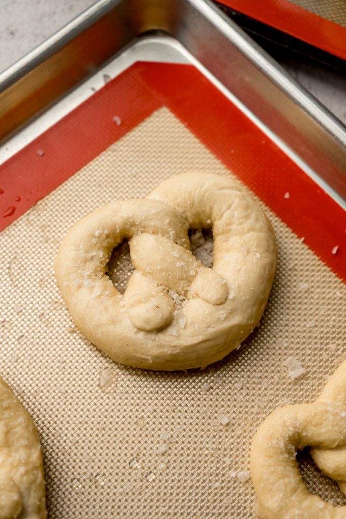 Soft pretzel on a baking sheet ready to bake.