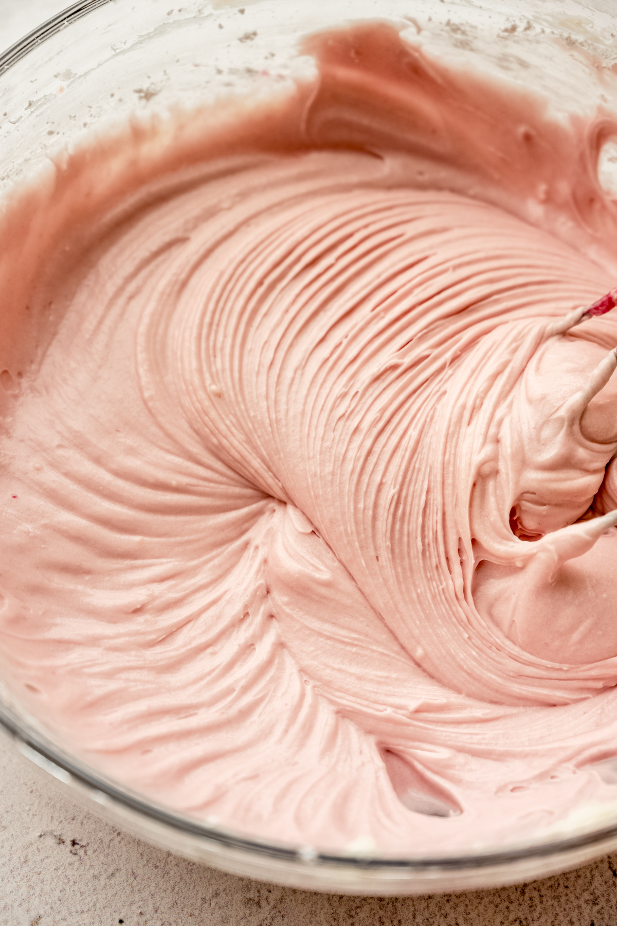 Blackberry cream cheese frosting in a bowl with a hand mixer.