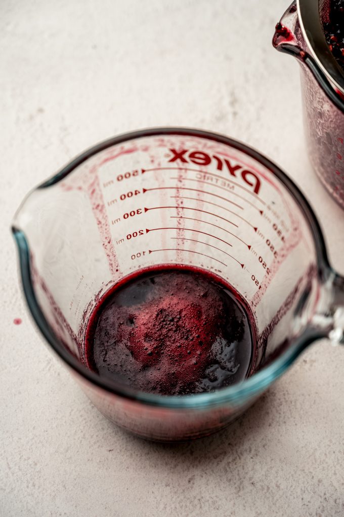 A measuring cup full of blackberry juice.