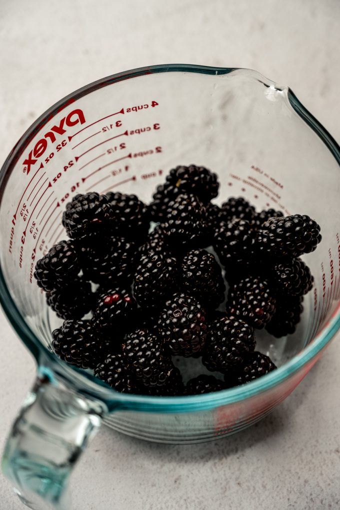 A large glass measuring cup with fresh blackberries in it.
