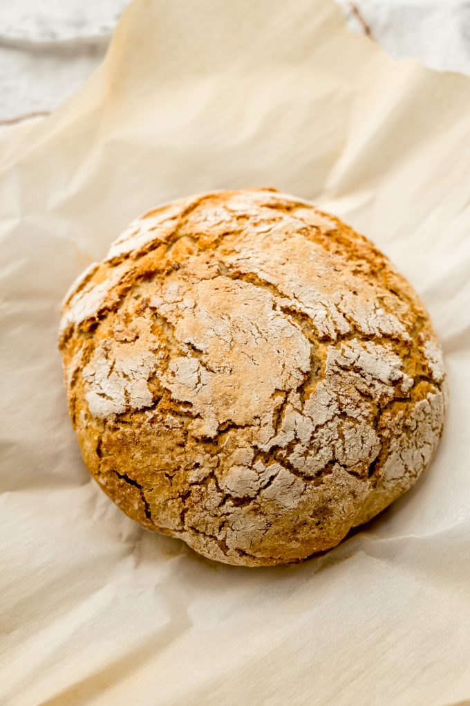 A loaf of no knead bread on a piece of parchment.