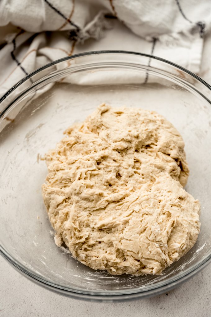 Shaggy bread dough in a glass bowl.