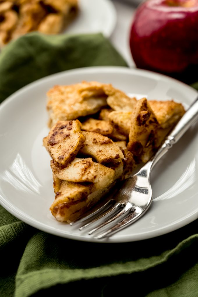 A slice of apple galette on a plate with a fork.