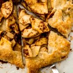 Aerial photo of someone holding a slice of apple galette with a pie server.