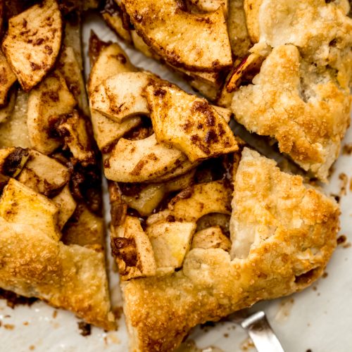 Aerial photo of someone holding a slice of apple galette with a pie server.