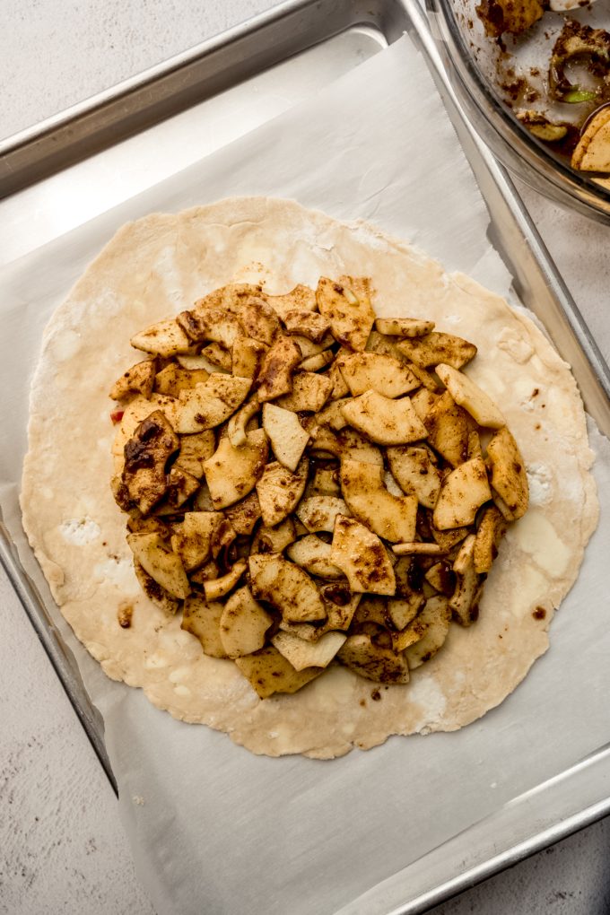 Aerial photo of a pie dough circle rolled out with apple galette filling in it.