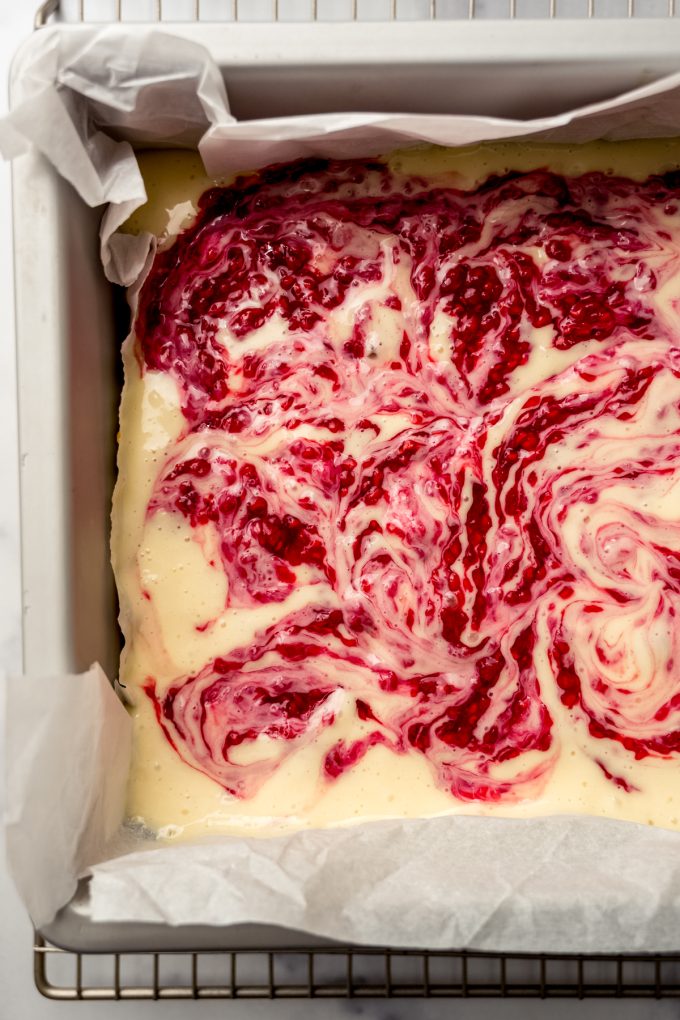 Aerial photo of raspberry cheesecake bars swirled with raspberry reduction.