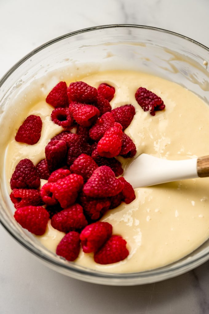 A bowl of raspberry cheesecake bar filling getting stirred with a spatula.