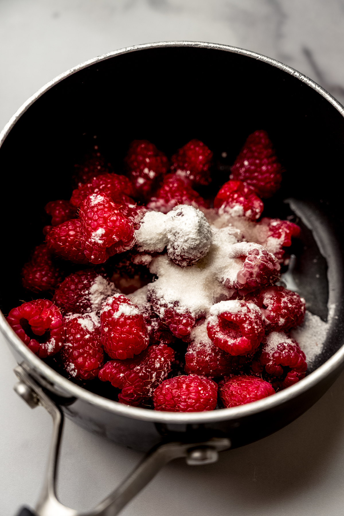 A saucepan of raspberries, flour, and sugar to make a raspberry reduction.